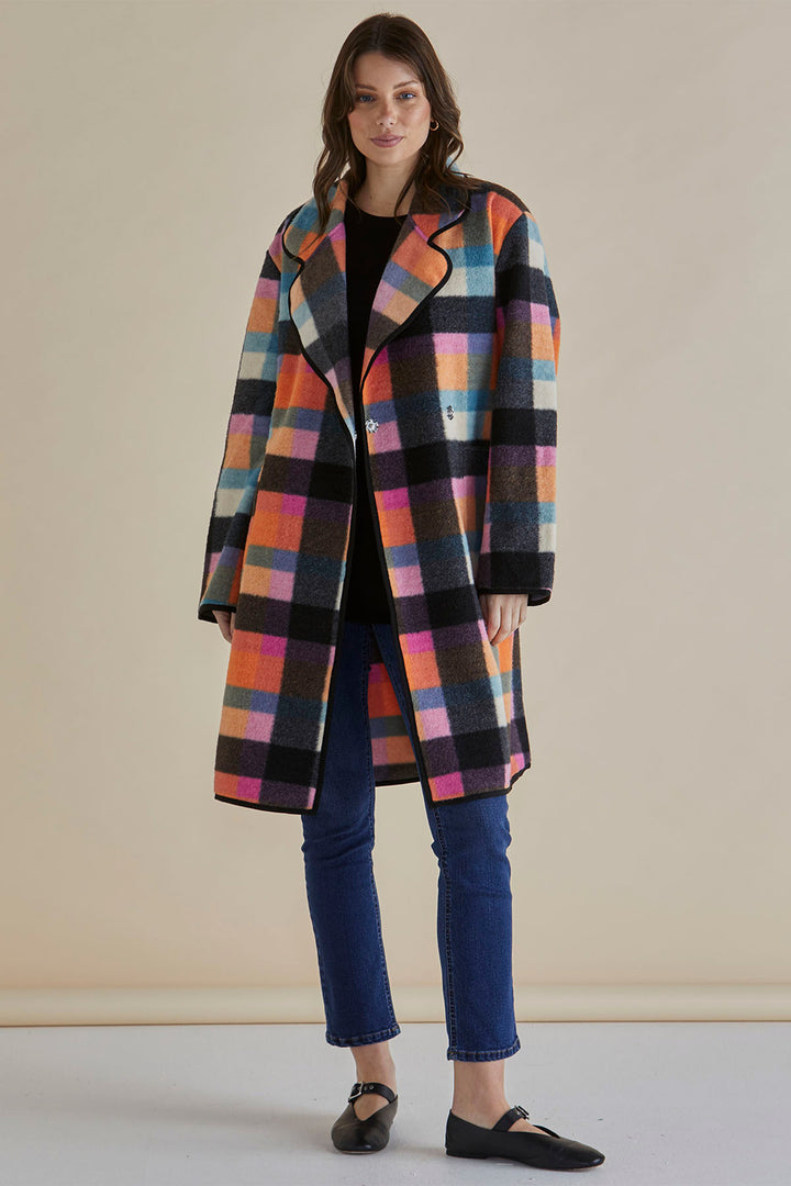 Woman wearing a colorful checkered coat against a beige background