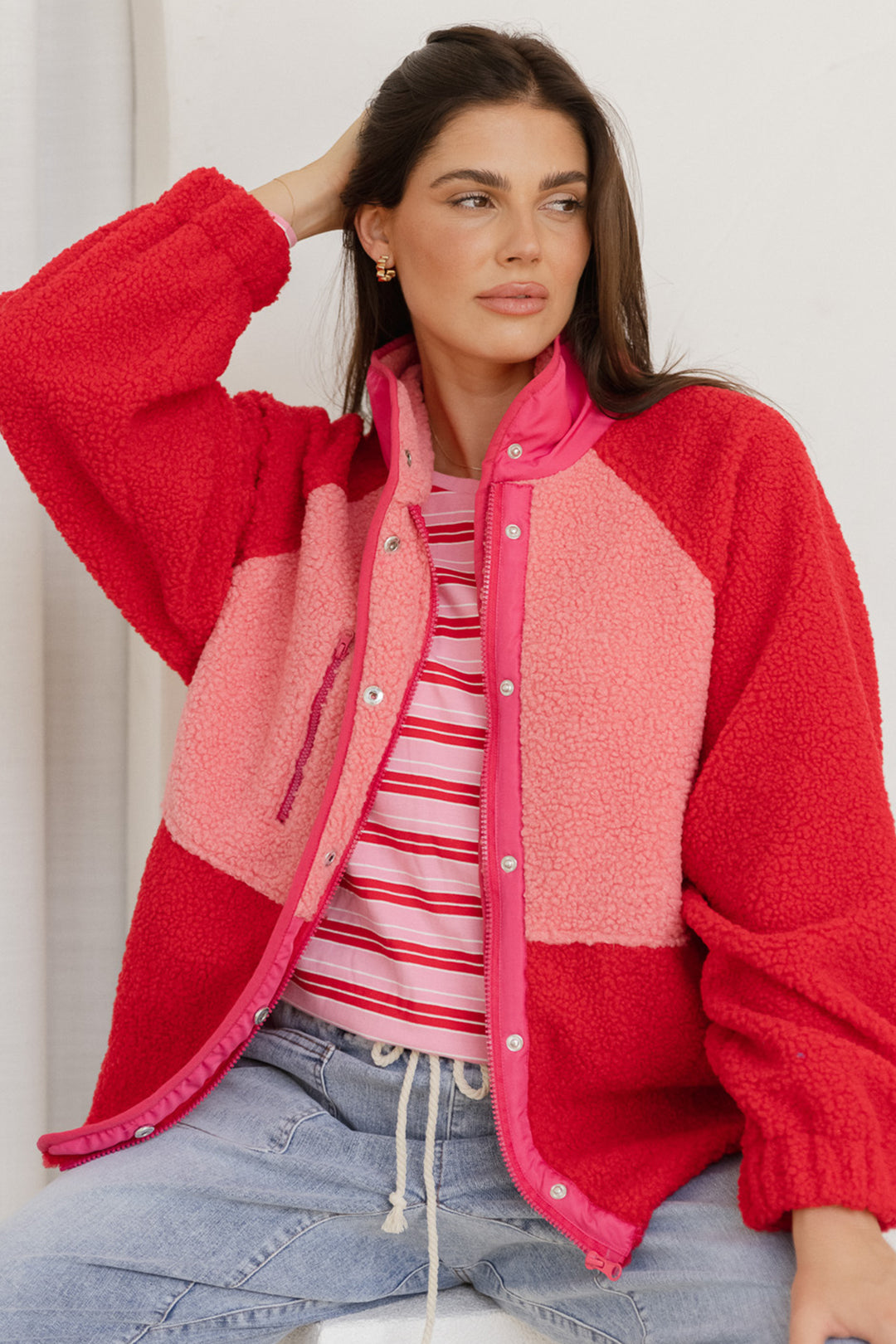 Woman wearing a red and pink fleece jacket with a white background