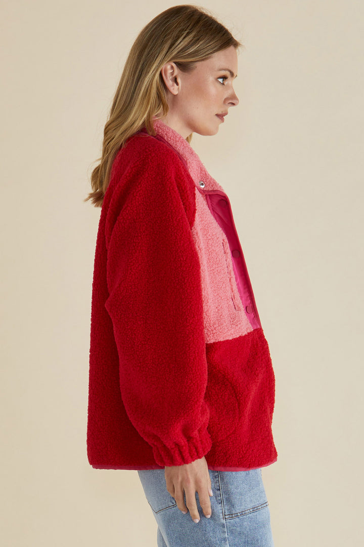 Woman wearing a red sweater with a pink inner lining on a beige background