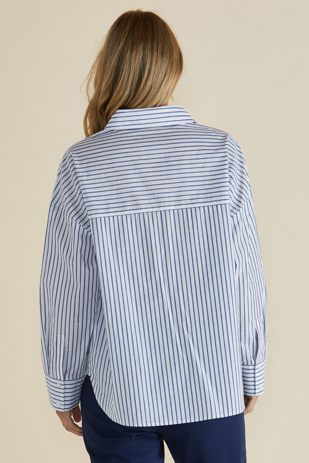 Person wearing a blue and white striped shirt against a beige background