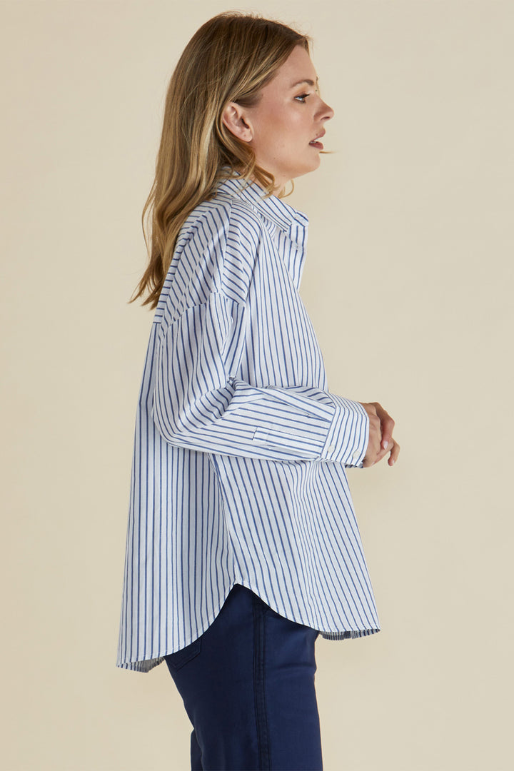 Woman wearing a blue and white striped shirt against a beige background