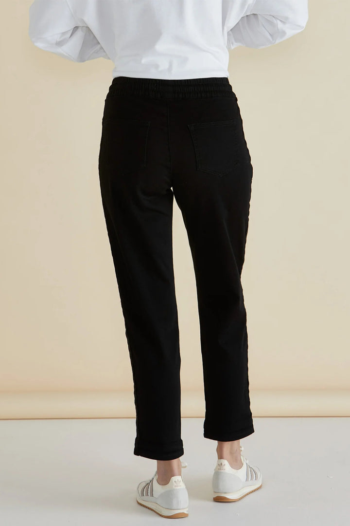 Person wearing black pants and a white top against a beige background