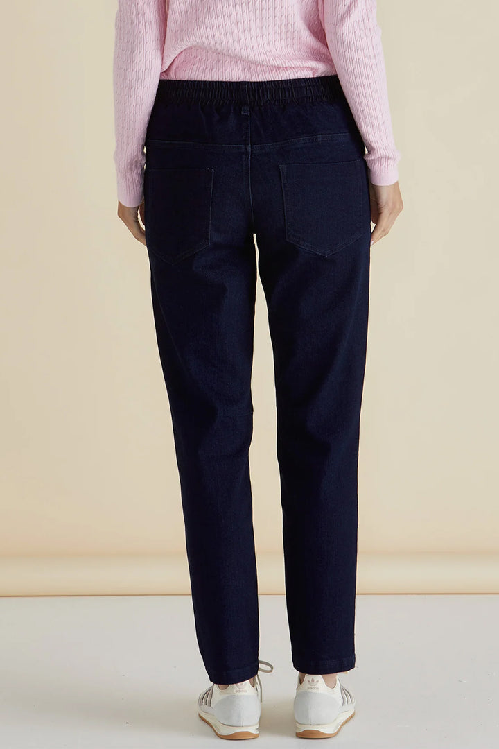 Person wearing navy pants and a pink sweater against a beige background