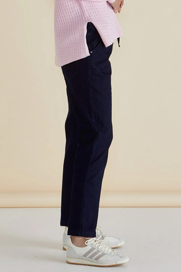 Person wearing navy pants, a pink shirt, and white sneakers on a beige background