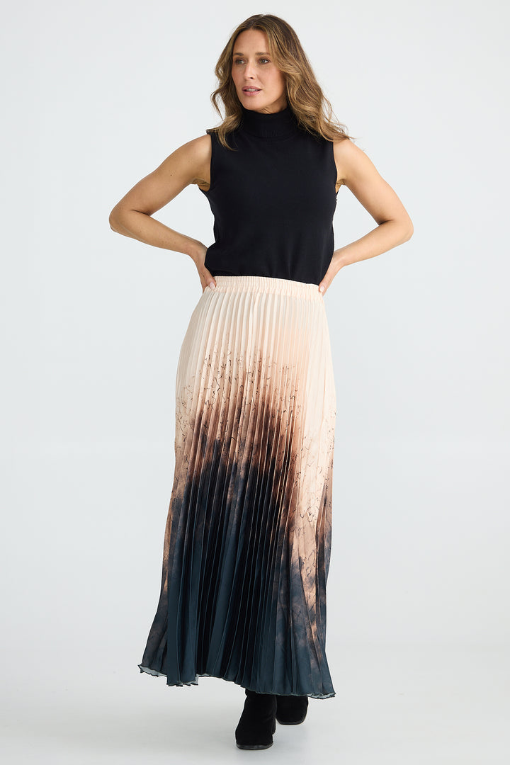 Woman wearing a black sleeveless top and a long, gradient skirt on a white background