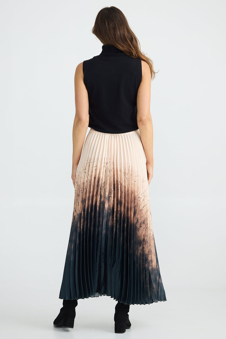 Woman wearing a black sleeveless top and pleated skirt with gradient color on a white background