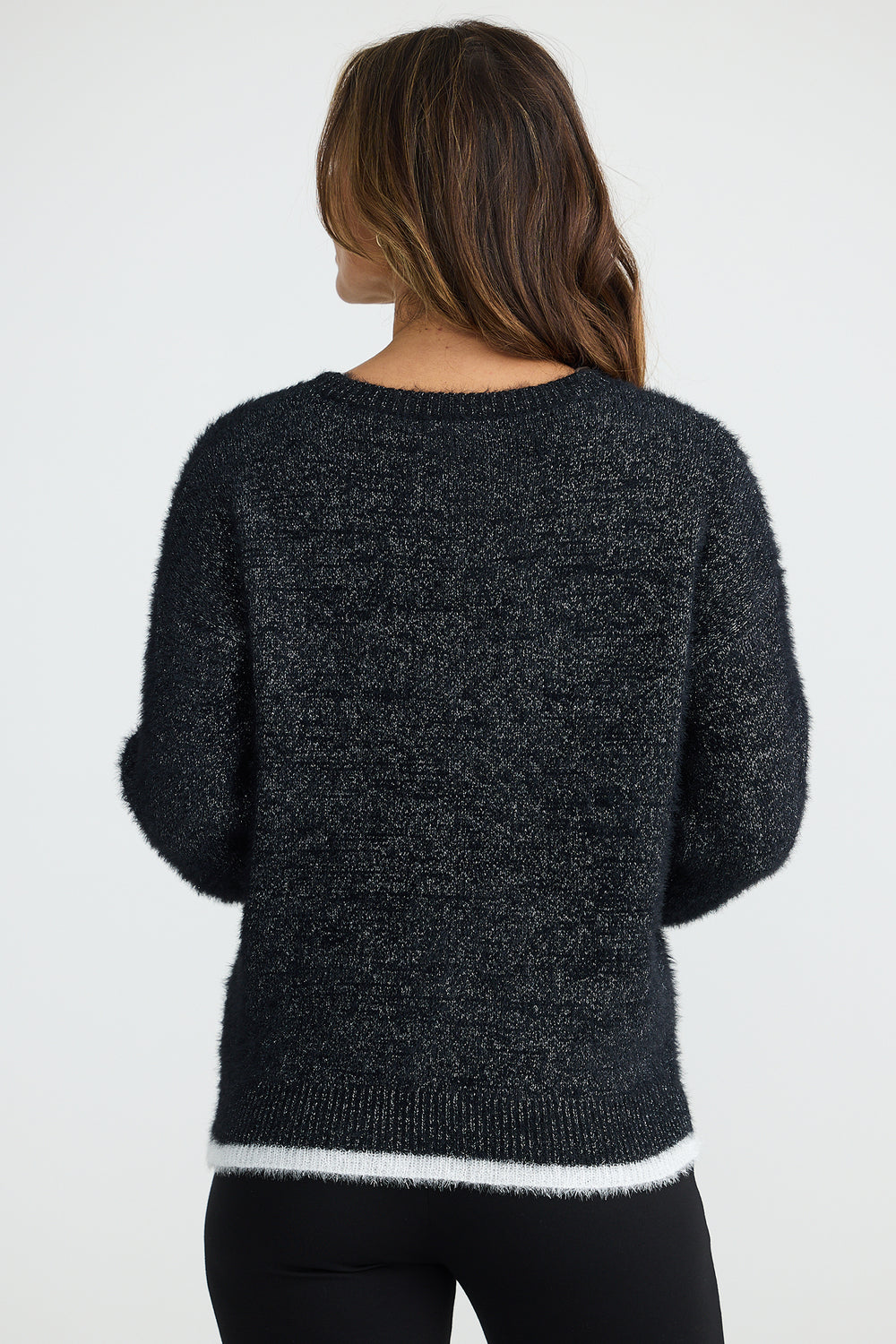 Person wearing a dark gray sweater with white trim on a plain background