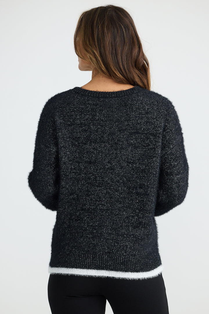 Person wearing a dark gray sweater with white trim on a plain background