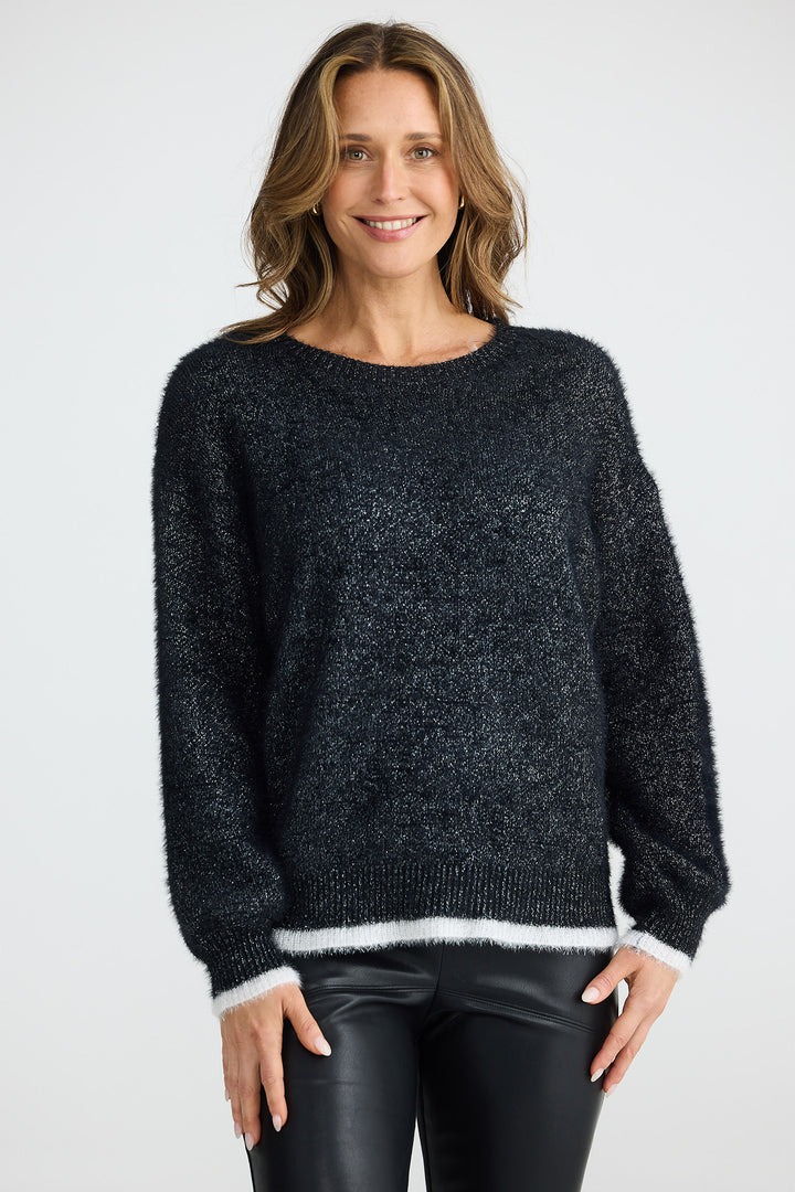 Woman wearing a dark gray sweater with white trim on a plain background