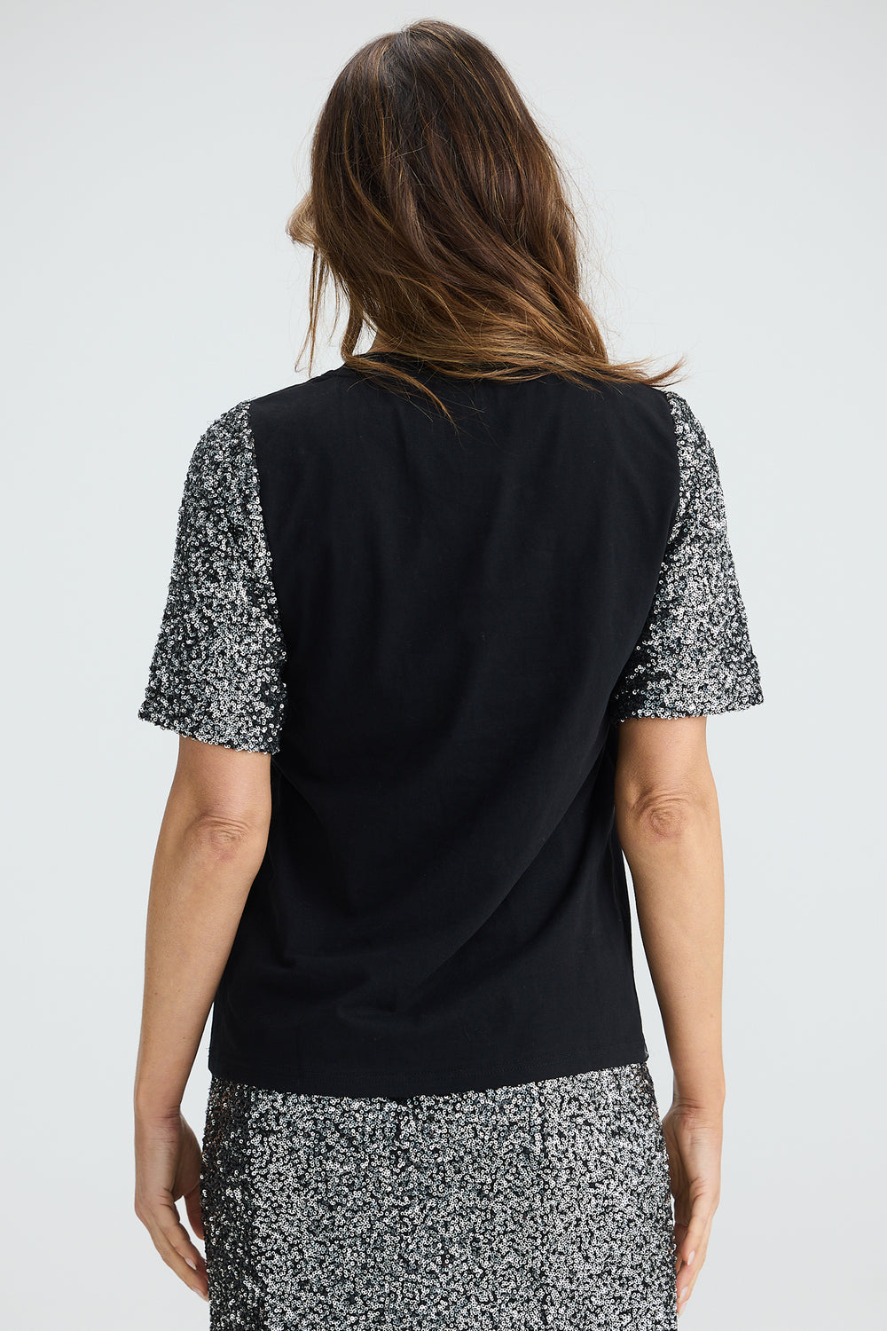 Woman wearing a black top with patterned sleeves on a white background