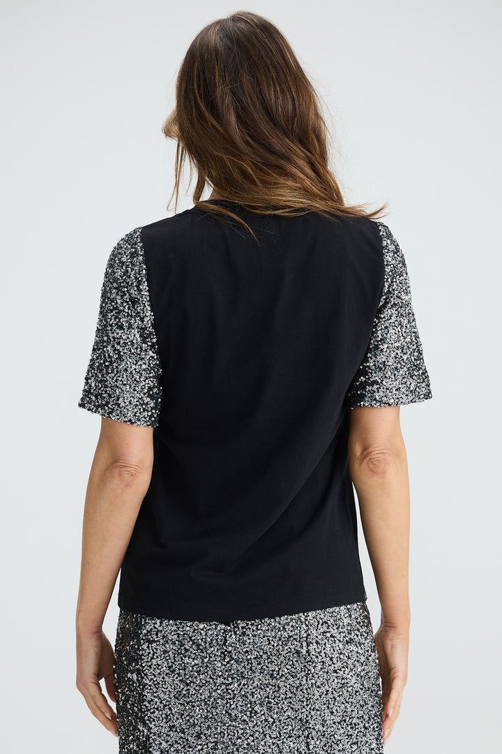 Woman wearing a black top with patterned sleeves on a white background