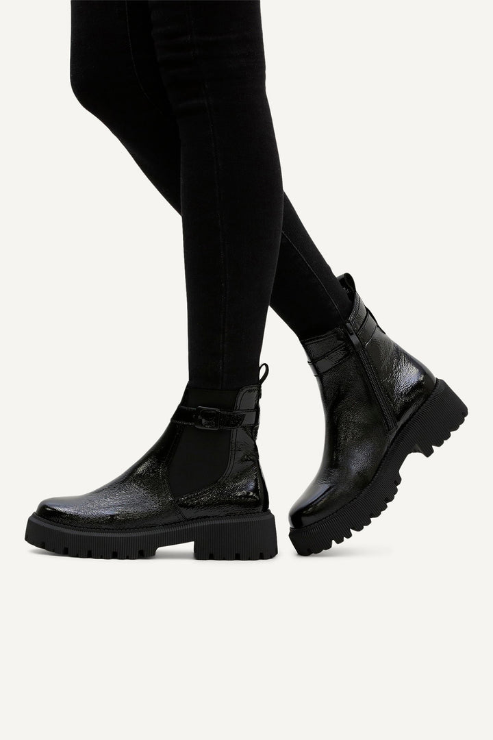 Black leather boots worn with black leggings on a white background