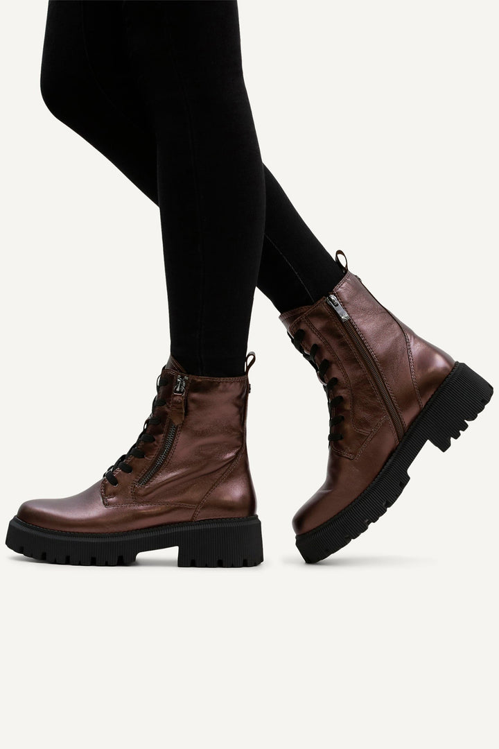 Brown leather boots worn with black leggings on a white background