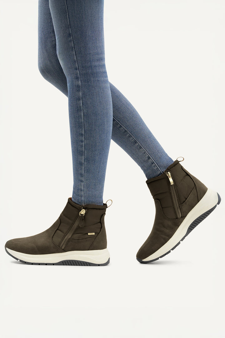 Khaki ankle boots worn with blue jeans on a white background