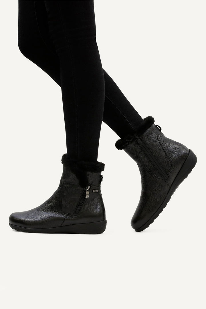 Black ankle boots worn with black leggings on a white background