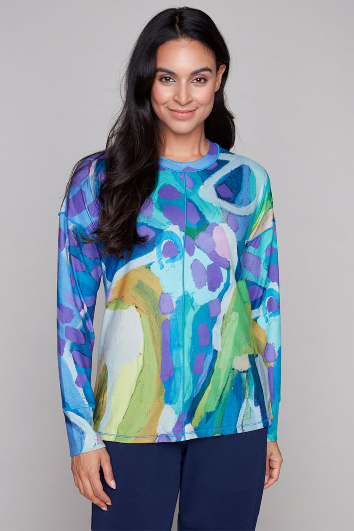 Woman wearing a colorful abstract patterned top against a plain background