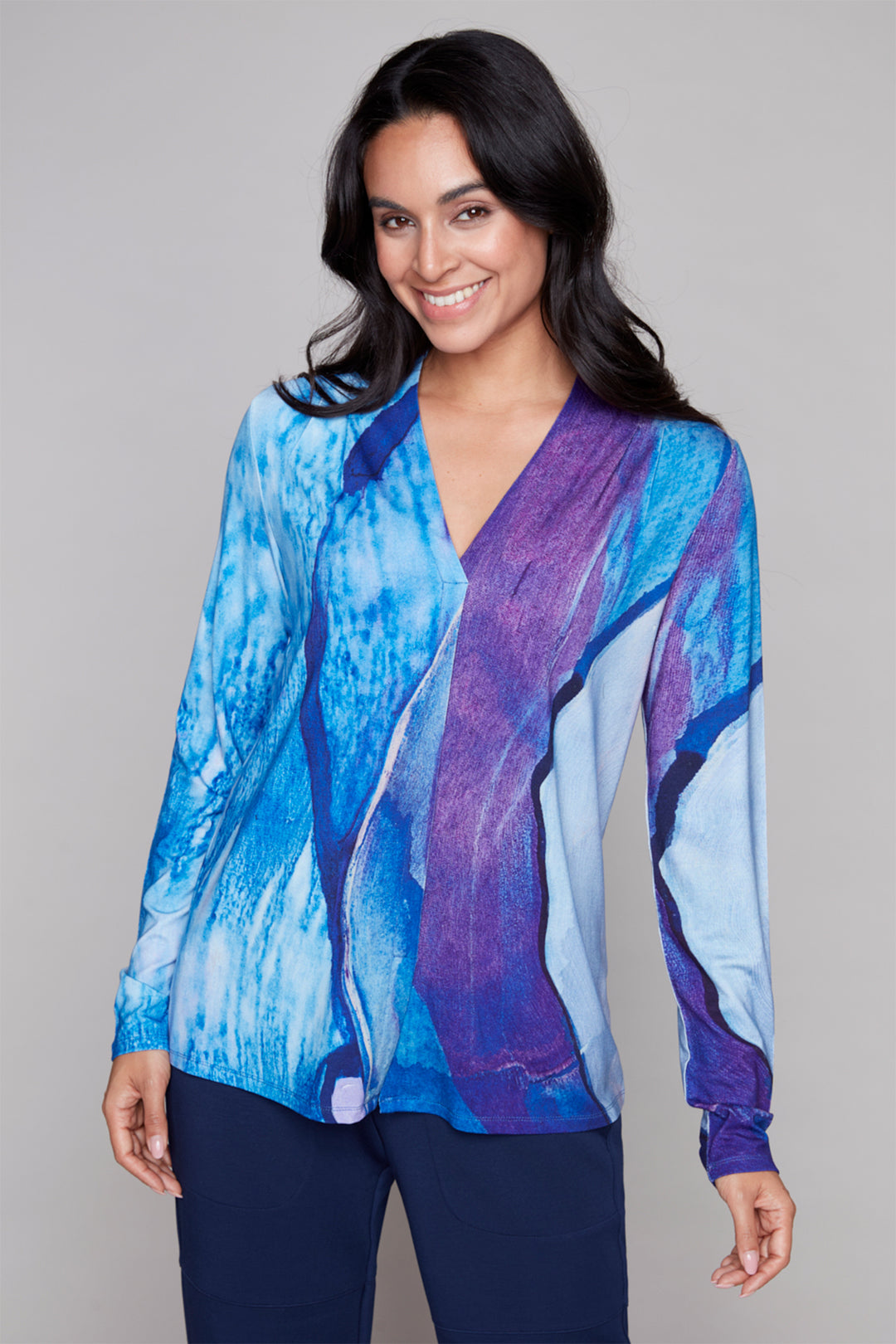 Woman wearing a blue and purple abstract patterned blouse against a gray background