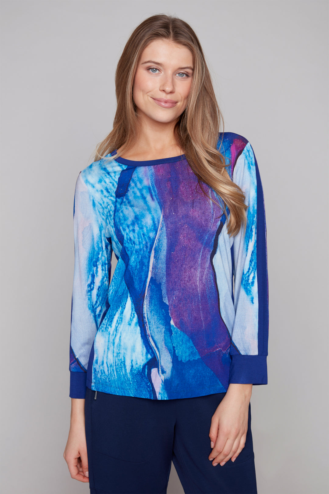 Woman wearing a blue and purple abstract patterned top against a plain background