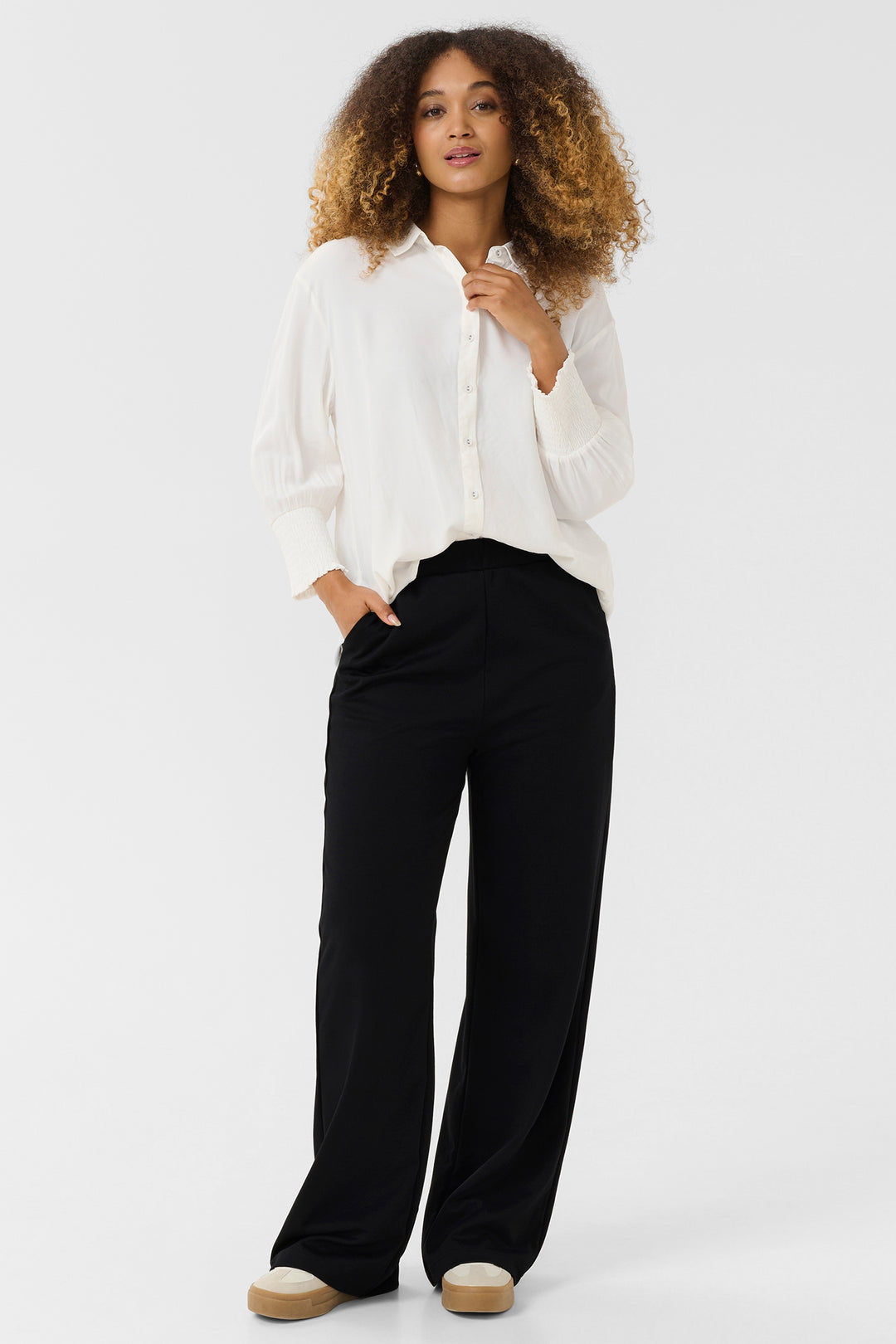 Woman wearing a white blouse and black pants on a white background