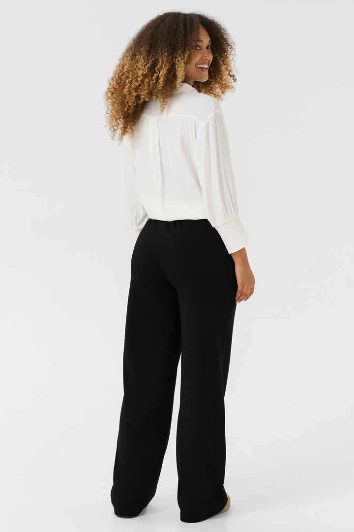 Woman wearing a white blouse and black pants on a white background