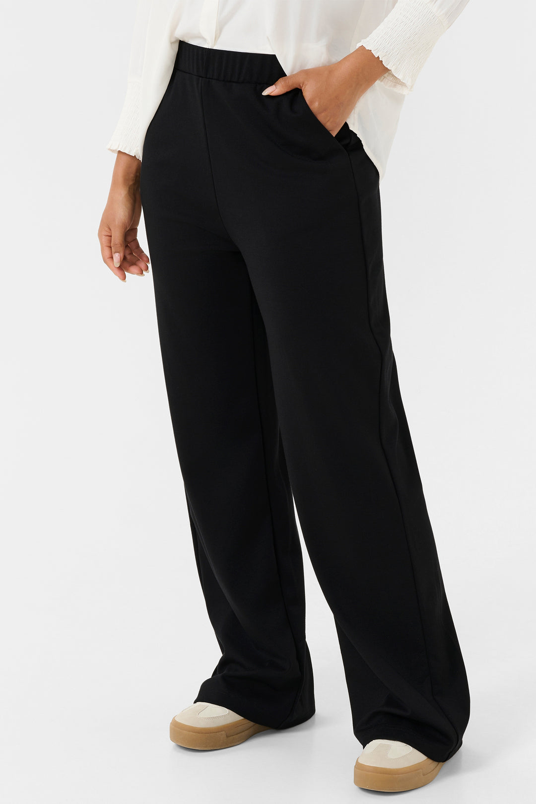 Person wearing black wide-leg pants with a white shirt on a light gray background