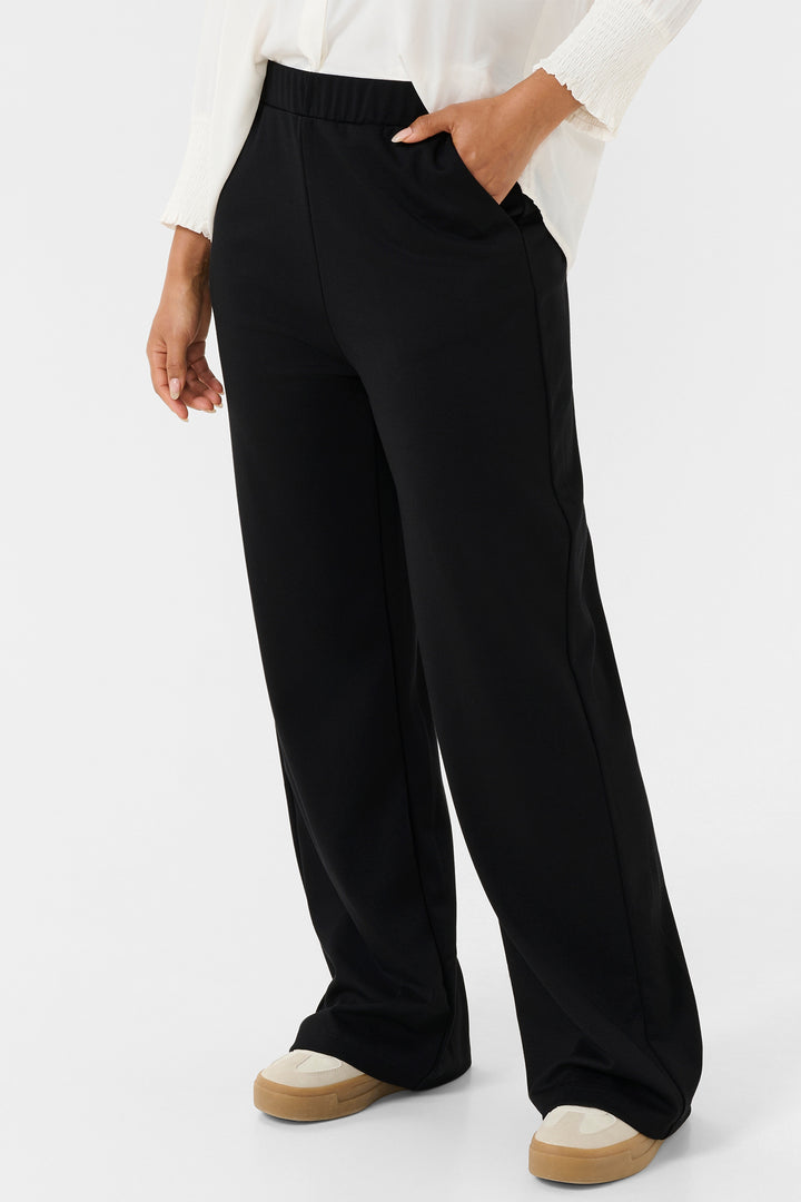 Person wearing black wide-leg pants with a white shirt on a light gray background