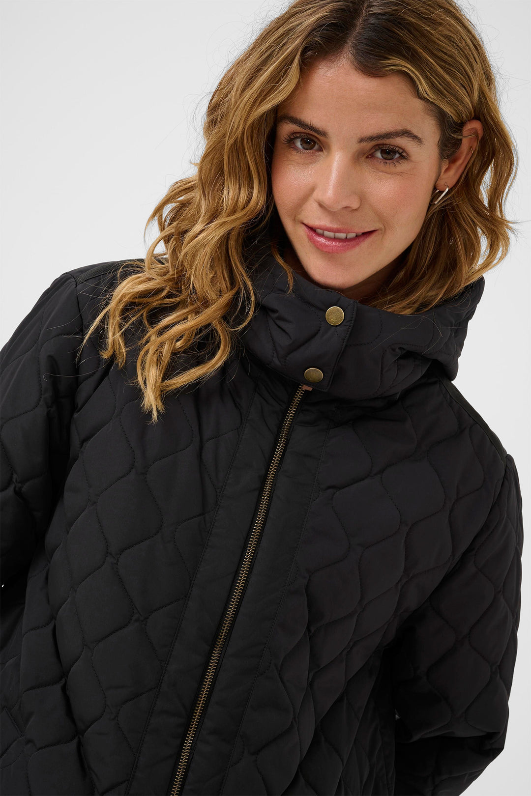 Woman wearing a black quilted jacket on a white background
