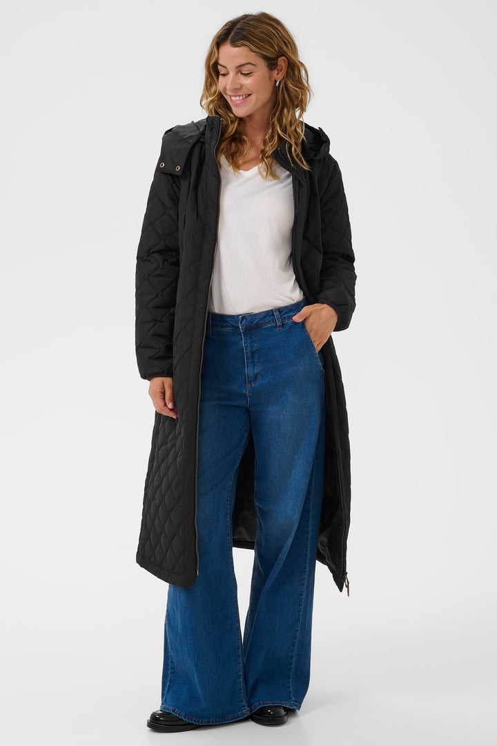 Woman wearing a black coat, white shirt, and blue jeans on a white background
