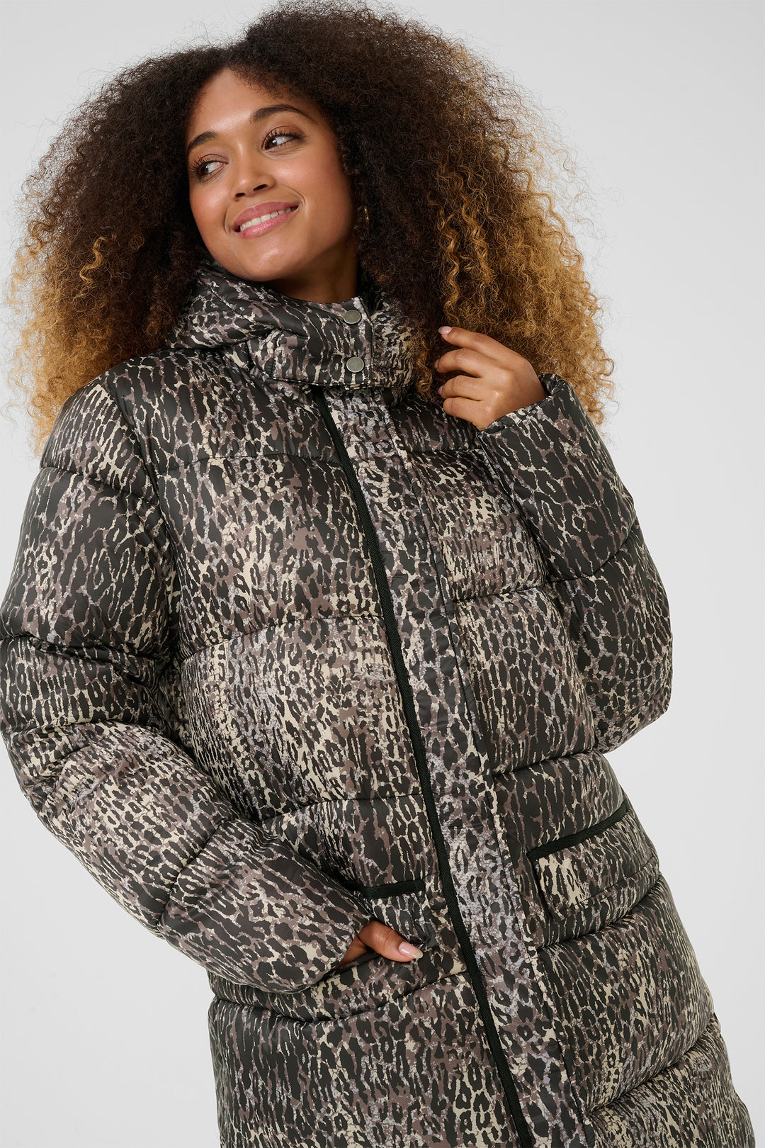 Person wearing a leopard print puffer coat on a white background