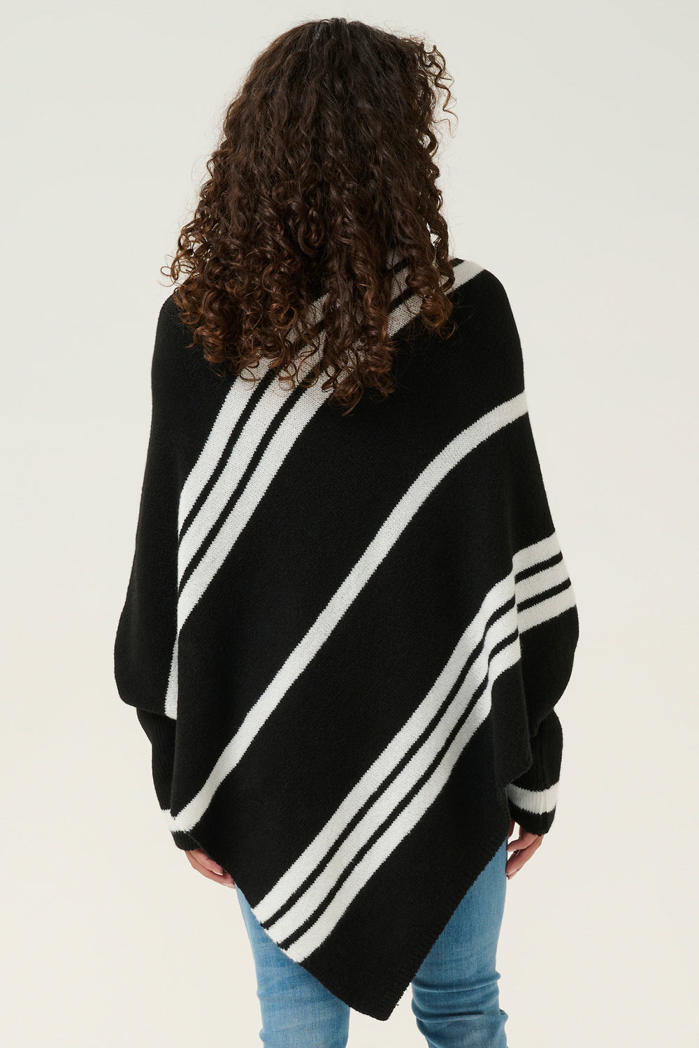 Person wearing a black poncho with white stripes on a plain background