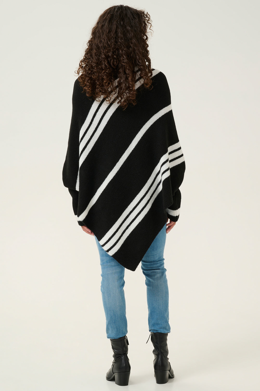 Person wearing a black and white striped poncho on a white background