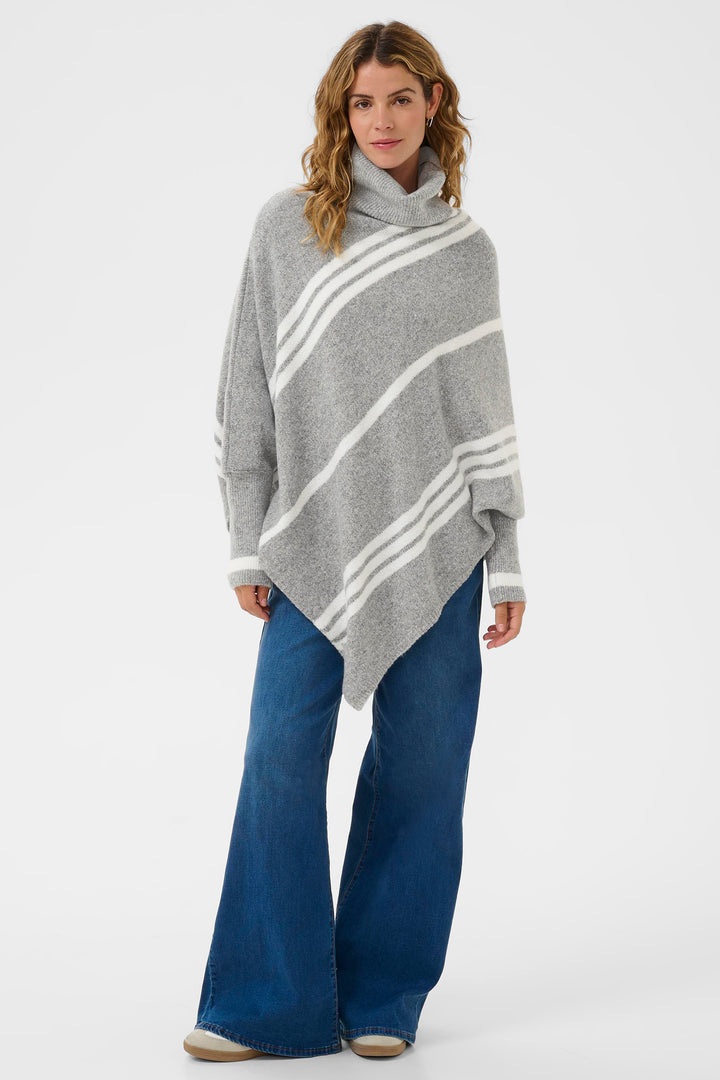 Woman wearing a gray poncho with white stripes and blue jeans on a white background