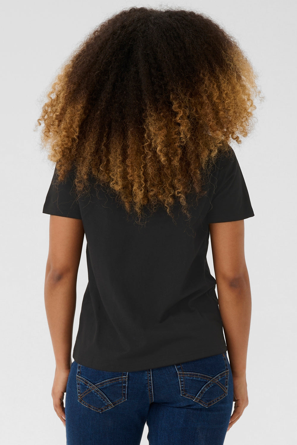 Person wearing a black t-shirt and blue jeans with a plain white background