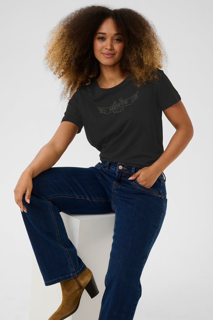 Woman wearing a black t-shirt and blue jeans sitting on a white background