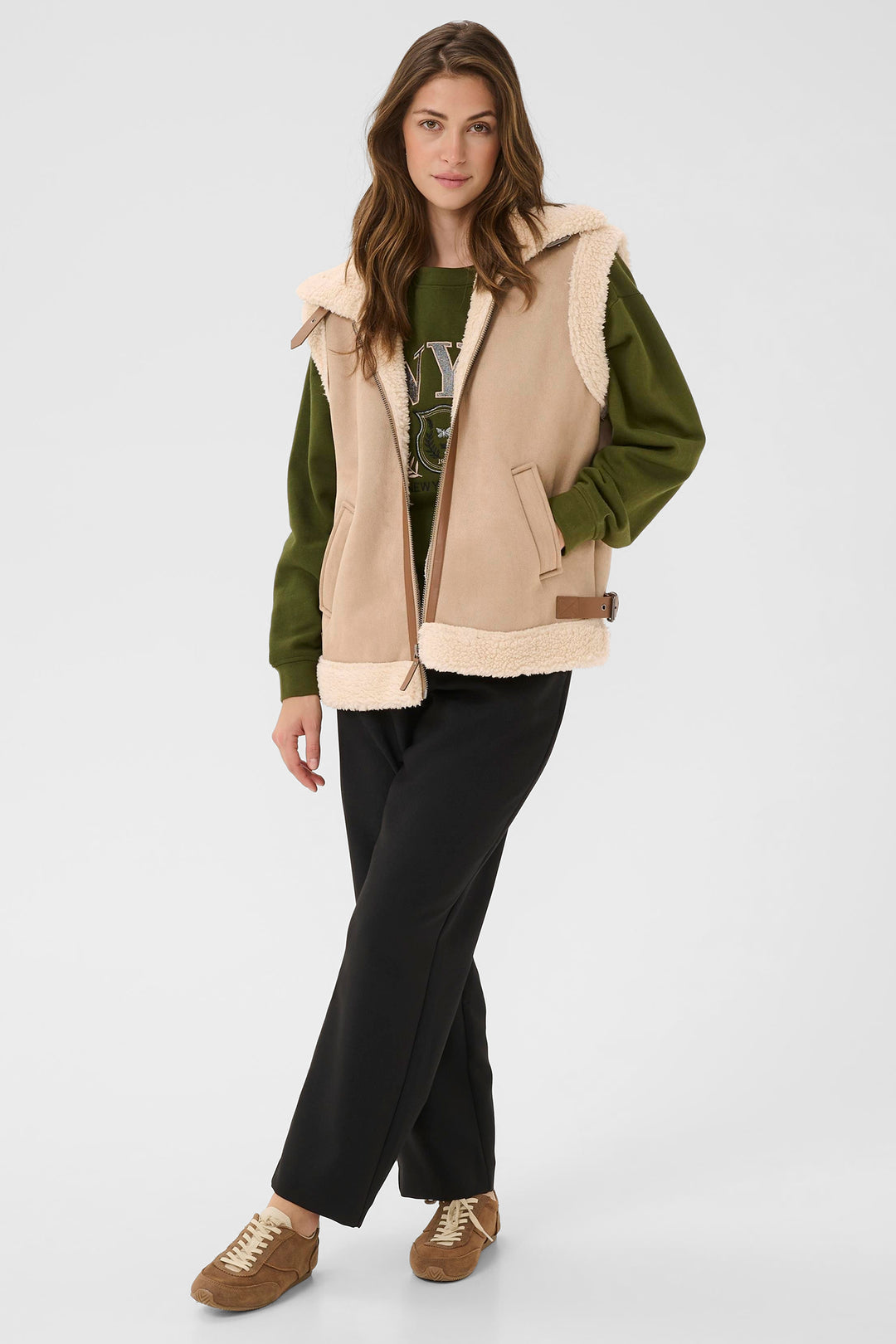 Woman wearing a green jacket with beige hood and black pants on a white background