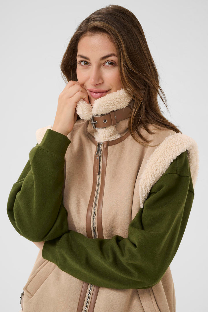 Woman wearing a green and beige jacket with a fur-lined hood on a white background