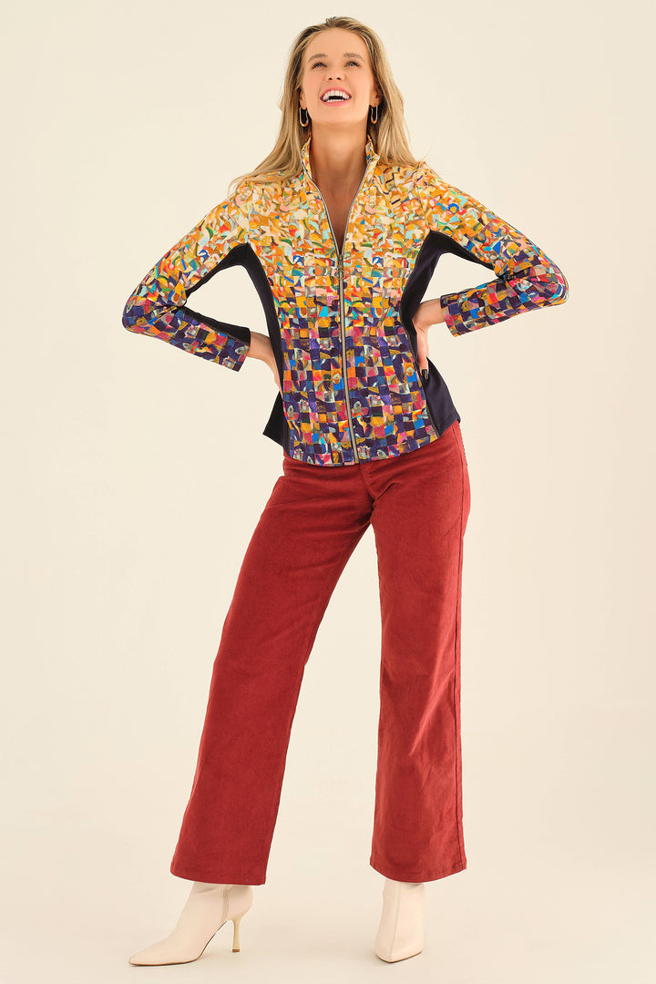 Woman wearing a colorful patterned jacket and red pants on a beige background
