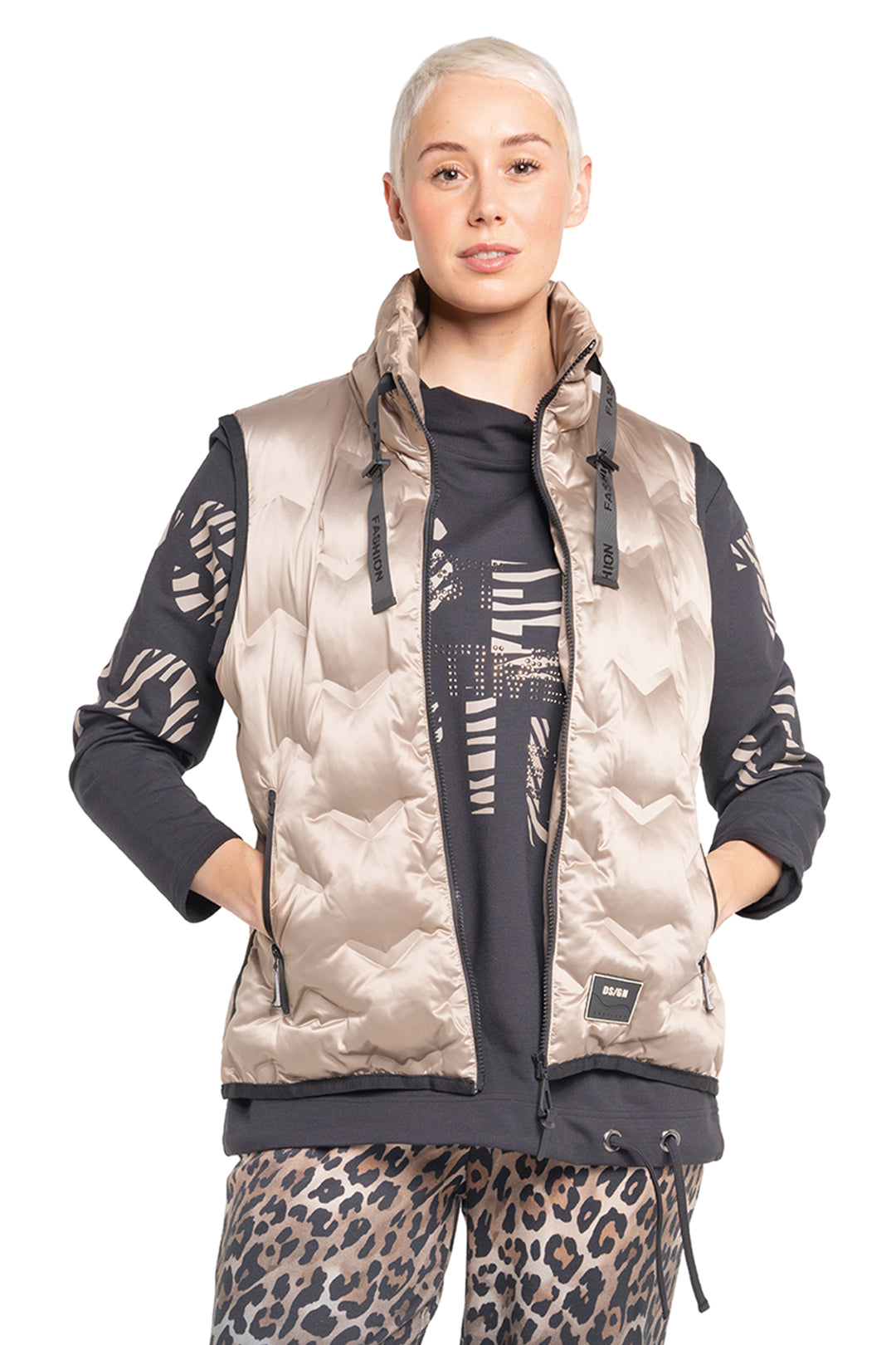 Person wearing a patterned jacket with leopard print pants on a white background