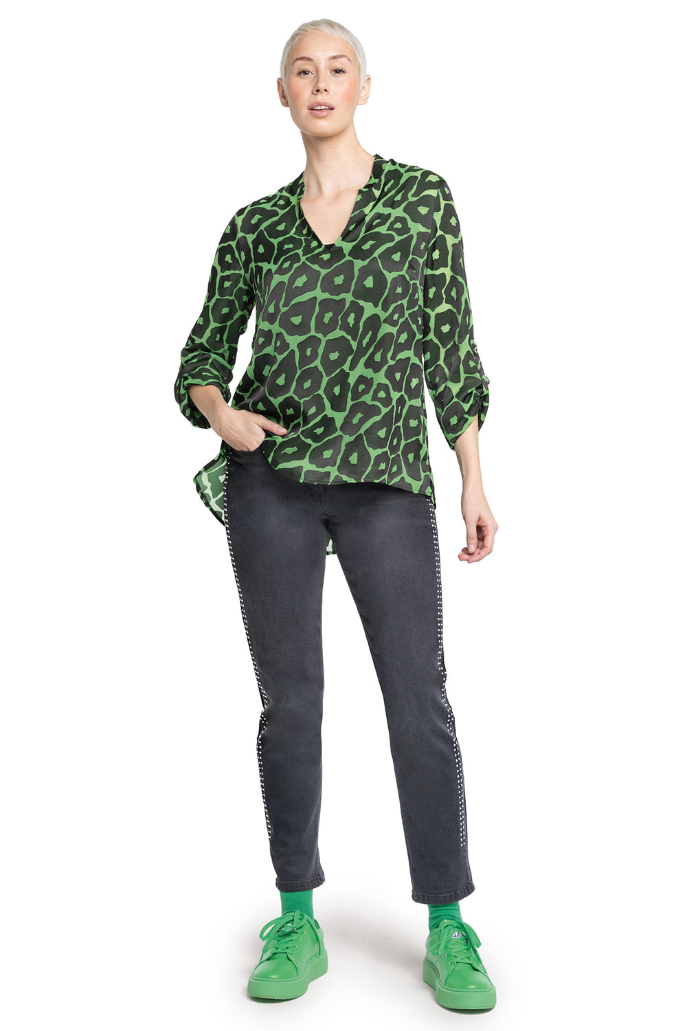 Person wearing a green leopard print top and gray pants on a white background