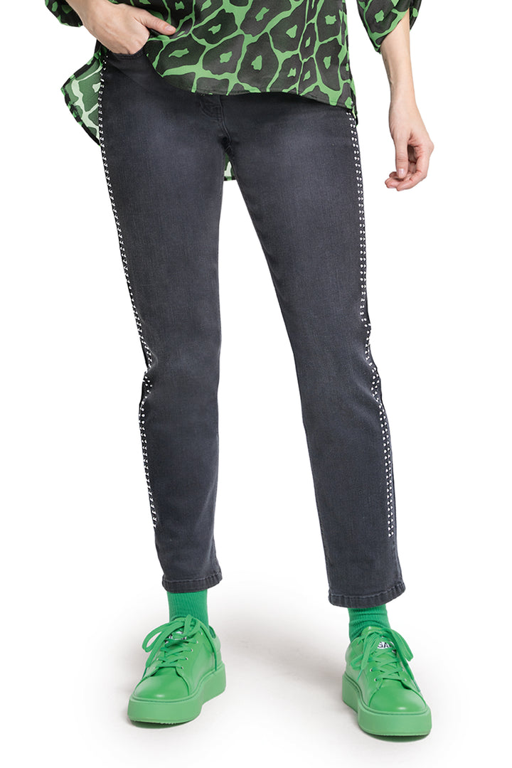 Person wearing black jeans with white stitching and green sneakers on a white background