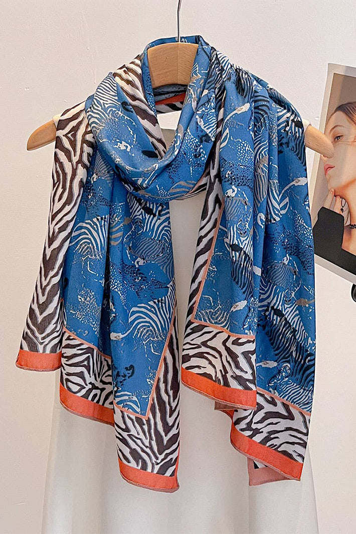 Blue scarf with zebra pattern draped over a hanger against a white background