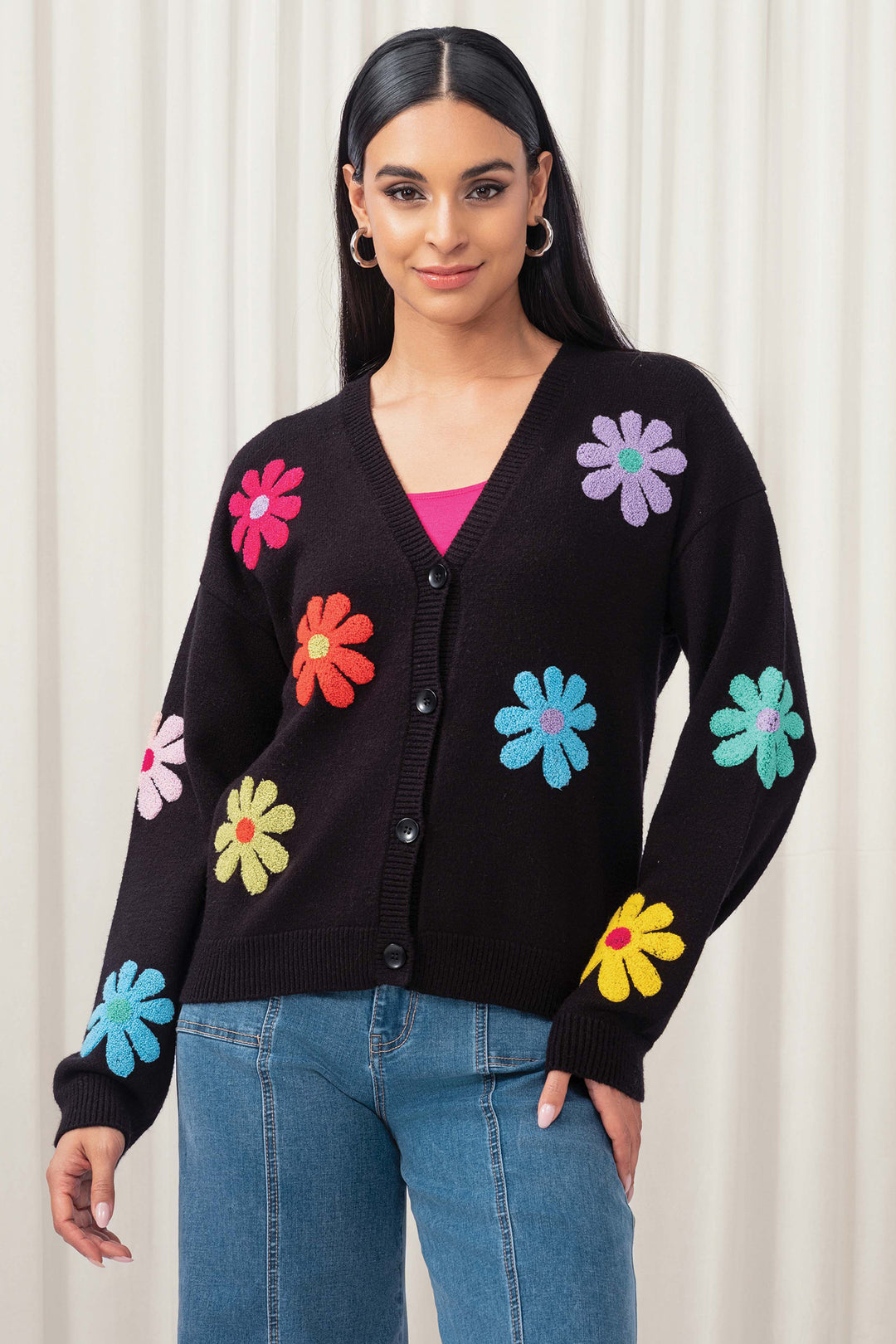 Woman wearing a black cardigan with colorful flower patterns against a white background