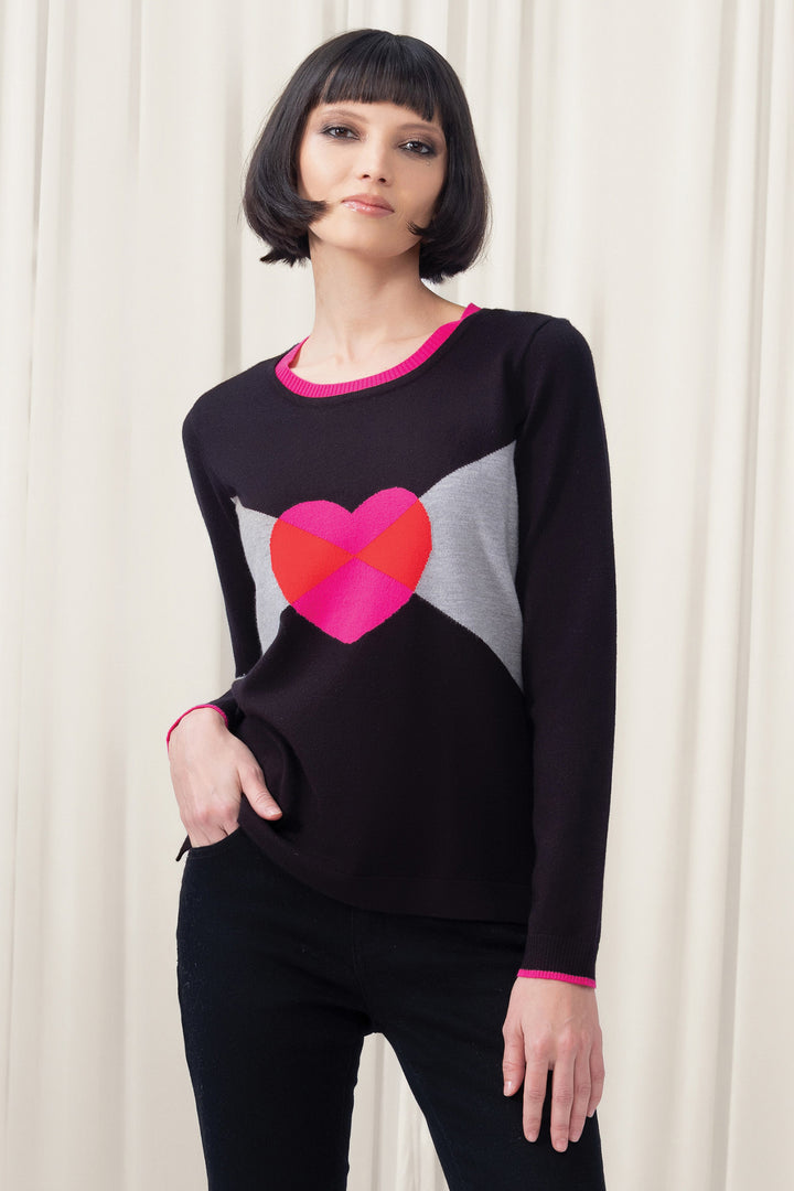 Woman wearing a black sweater with a pink heart design against a white curtain background