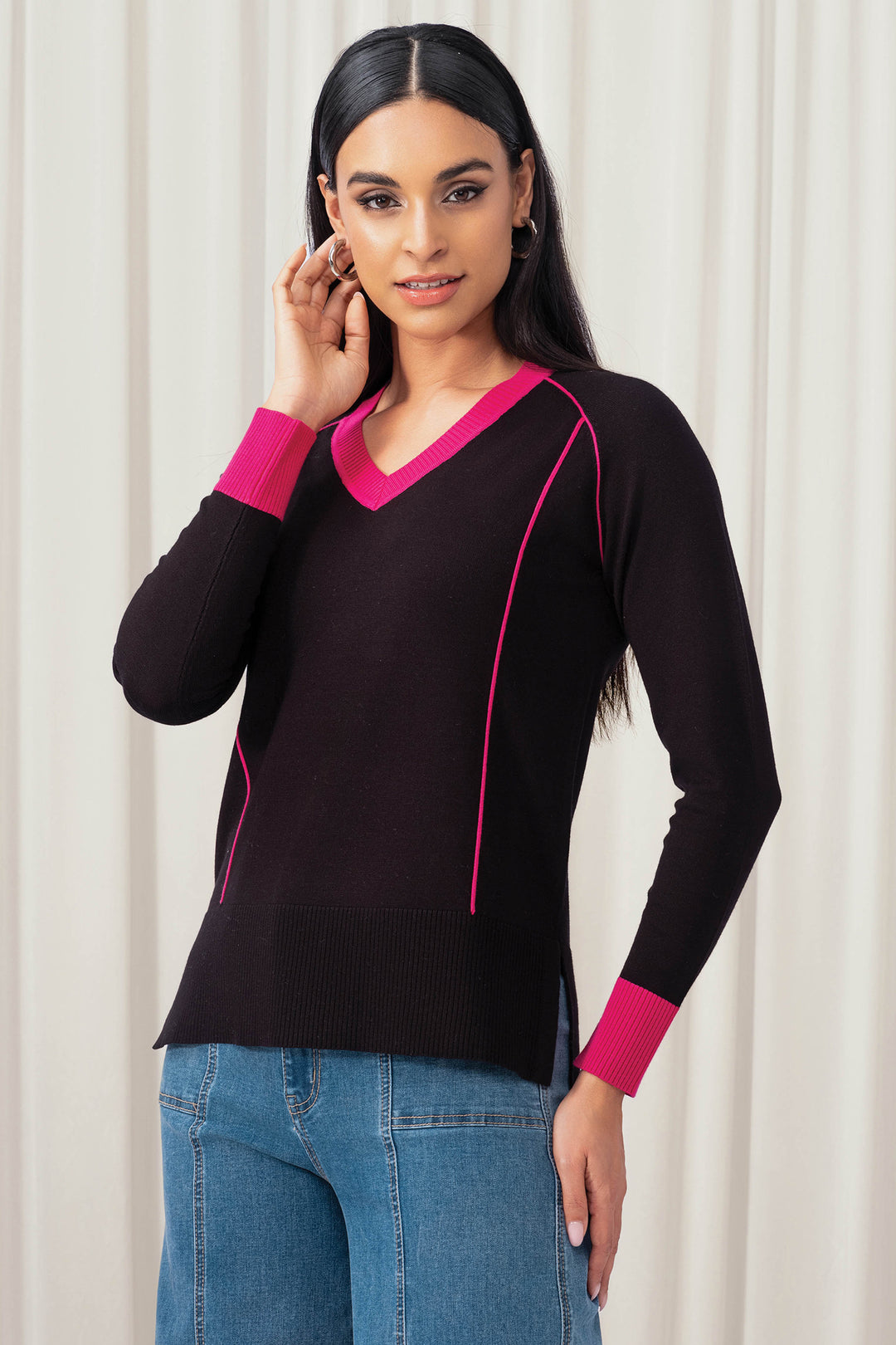 Woman wearing a black sweater with pink trim against a white background