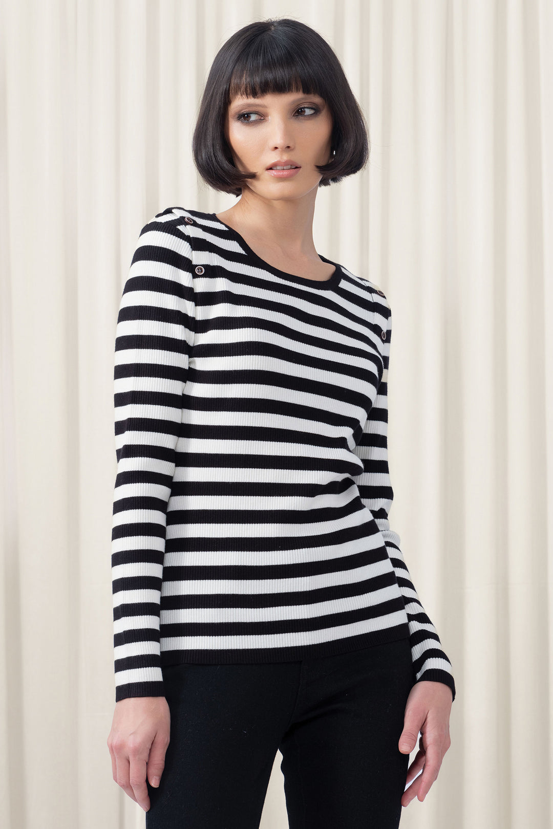 Woman wearing a black and white striped long-sleeve shirt against a white background