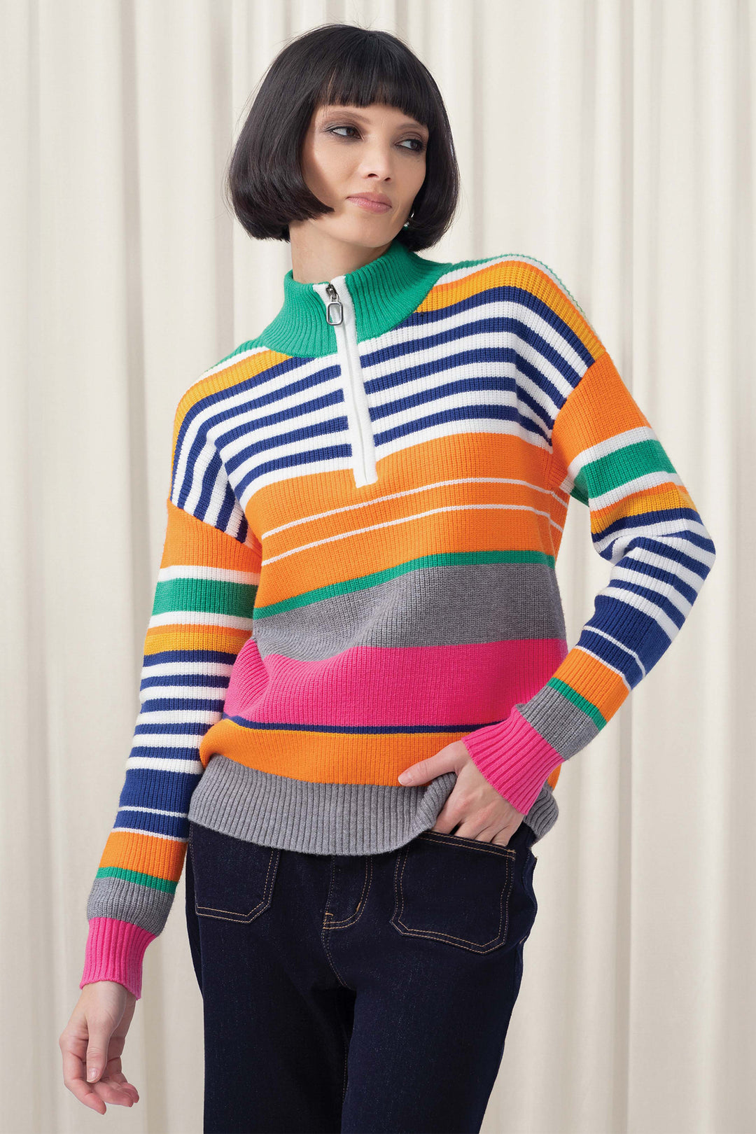 Woman wearing a colorful striped sweater against a white curtain background