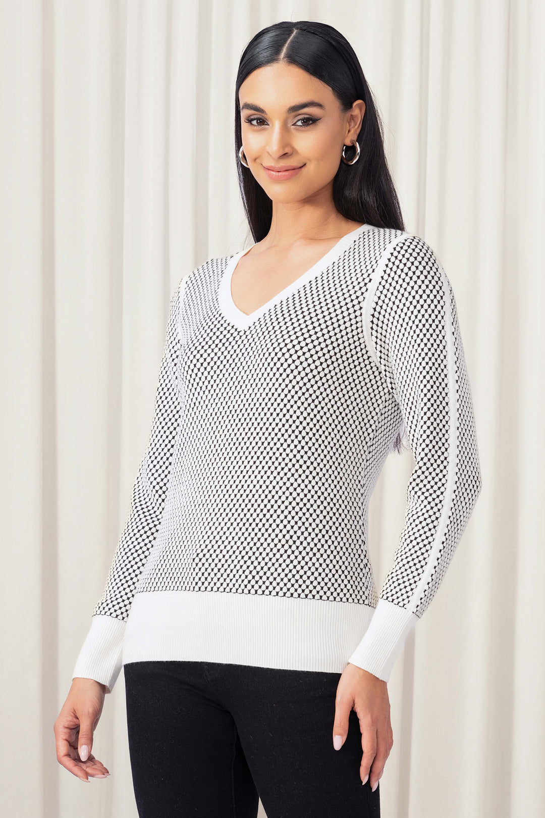 Woman wearing a black and white patterned sweater against a plain background