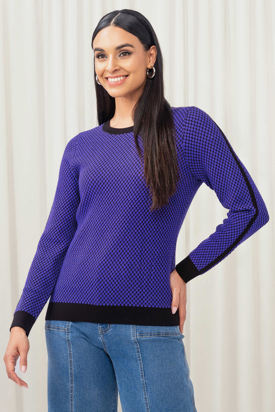 Woman wearing a purple textured sweater with black accents against a white background