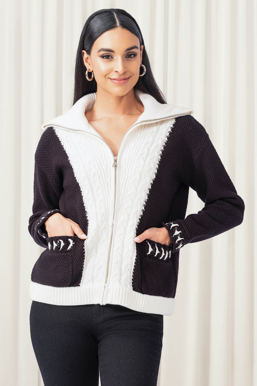 Woman wearing a black and white zip-up hoodie with decorative cuffs against a white background