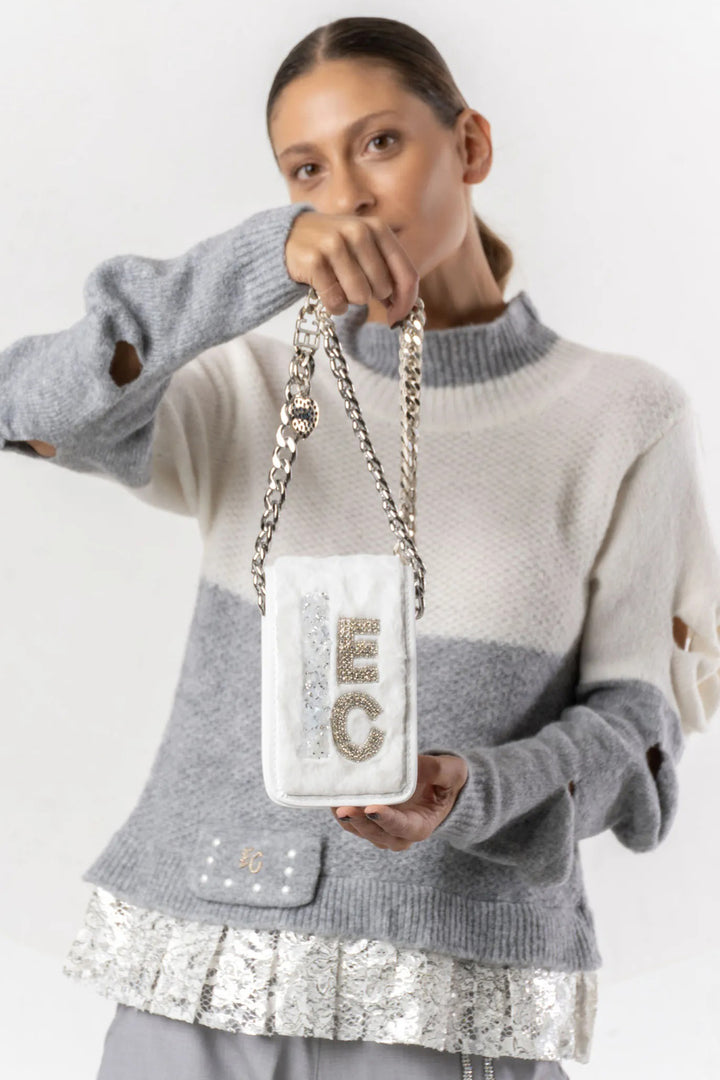 Person holding a white handbag with 'ICE' lettering against a light gray background